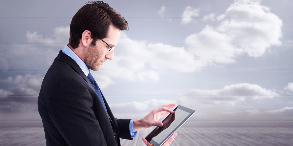 Businessman standing while using a tablet pc against clouds in a room-2